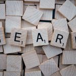 Wooden letter tiles arranged to spell learn on a background of scattered tiles.